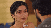 a man is touching a woman 's face with a napkin .