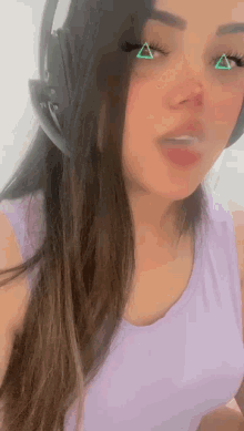 a woman wearing headphones and a purple tank top with triangles on her eyes