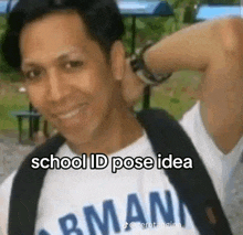 a man wearing a school id pose idea t-shirt is smiling and holding his hand to his head .