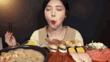 a woman is eating a variety of sushi and soup with chopsticks .