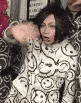 a woman wearing a sweater with smiley faces on it is standing next to a man .
