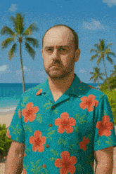 a man in a blue shirt with red flowers on it stands on a beach