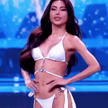 a woman in a white bikini is dancing on a stage .
