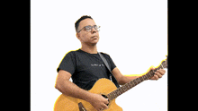 a man wearing glasses and a black shirt playing an acoustic guitar