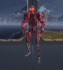 a red robot is holding a gun in front of a landscape