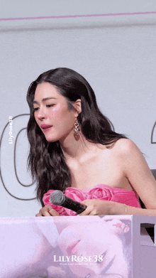 a woman in a pink strapless dress is holding a microphone