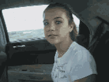 a girl is sitting in the back seat of a car looking out the window .