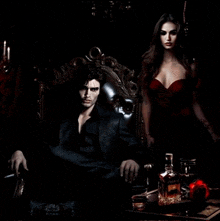 a man is sitting in a chair next to a woman in a red dress and a bottle of whiskey