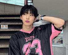 a young man wearing a black and pink shirt with the number 23 on it