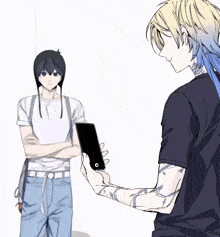 a man is holding a cell phone in front of another man with his arms crossed