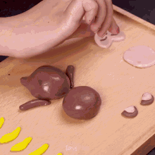 a person is making a dog out of clay on a wooden table
