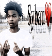 a young man is giving the middle finger in front of a picture that says sybau