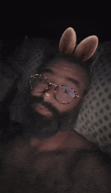 a man with glasses and bunny ears is laying on a bed