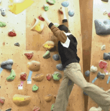 a man climbs a climbing wall with a sticker on it that says ' warning ' on it