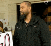 a man with a beard is holding a sign that says ' go ' on it .