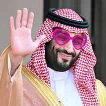 a man wearing heart shaped sunglasses is waving