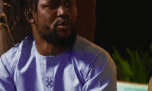 a man with dreadlocks and a beard wearing a blue shirt