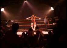 a referee stands in the middle of a wrestling ring surrounded by fans