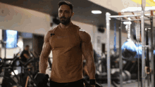 a man in a tank top with the word reebok on it is lifting dumbbells in a gym