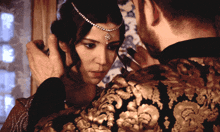 a man is touching a woman 's head with a headpiece