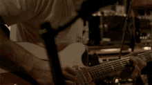 a man in a white shirt is playing an acoustic guitar