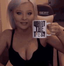 a woman in a black bra is holding a mug that says what the ties