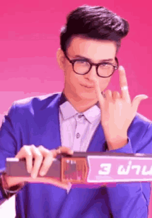 a man wearing glasses and a blue suit is holding a sign with the number 3 on it