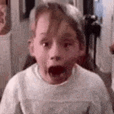 a young boy with his mouth open is making a surprised face .