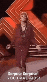 a woman in a red dress is dancing on a stage and says surprise surprise ! you have aids .