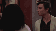 a man and a woman looking at each other with a window in the background