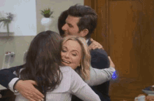 a man and two women are hugging each other .