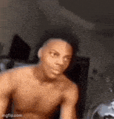 a shirtless man is making a funny face in a bedroom .