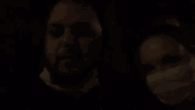 a man and a woman wearing face masks in a dark room .
