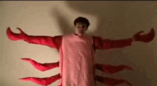 a man in a lobster costume is standing in front of a white wall .