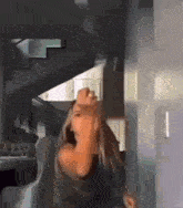 a woman is dancing in a room in front of a staircase .