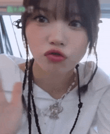 a woman wearing a white shirt and a necklace is making a face .