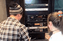 a man and a woman are looking at a stack of equipment