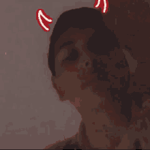 a man with devil horns on his head is taking a selfie in a bathtub .
