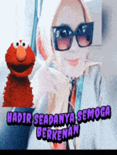 a woman wearing sunglasses and a scarf is next to elmo and the words hadir seadanya semoga berkenan