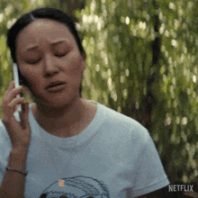 a woman talking on a cell phone with netflix written on the bottom of her shirt