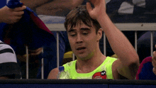 a man wearing a neon green tank top that says dec coco on it