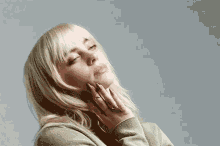 a close up of a woman 's face with her eyes closed and her hands on her face .