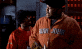 a man wearing an orange sweatshirt with the word john on the front
