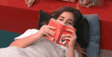a woman is laying on a bed reading a book called a little book of information