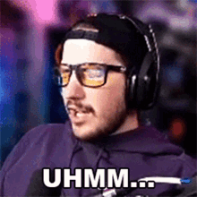 a man wearing headphones and glasses is sitting in front of a microphone .