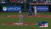 a baseball game is being played with an ad for vada pharmaceuticals in the background