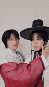 two young men wearing traditional korean clothing and hats pose for a photo