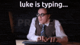 a man wearing glasses and a vest is typing on a computer keyboard
