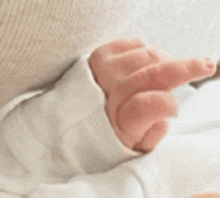 a close up of a baby 's hand with a white sleeve .