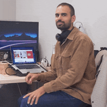 a man sits at a desk with a laptop and a monitor that says ' coca cola ' on it